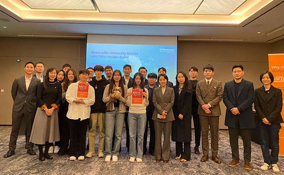 A group of 22 members of the Newcastle University Korea Alumni Network. All dressed smartly and smiling at the camera at an alumni event. 